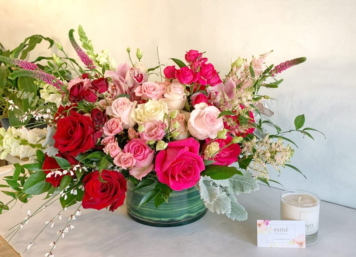 Large bouquet of pink and red roses in a green glass vase