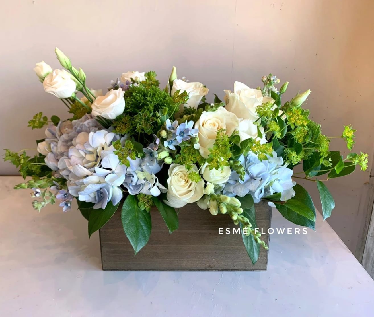 Cream roses and blue hydrangeas in a wooden box