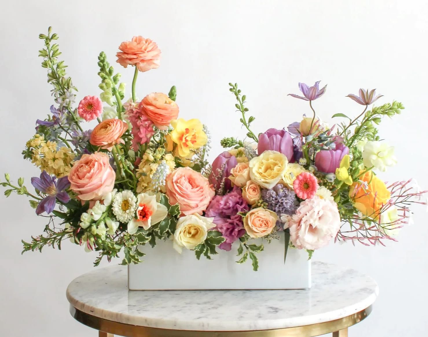 Mixed pastel flower arrangement in a white rectangular vase