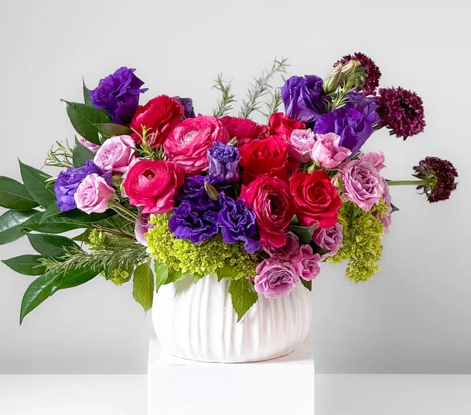 Bouquet of pink, red, and purple flowers in a white vase