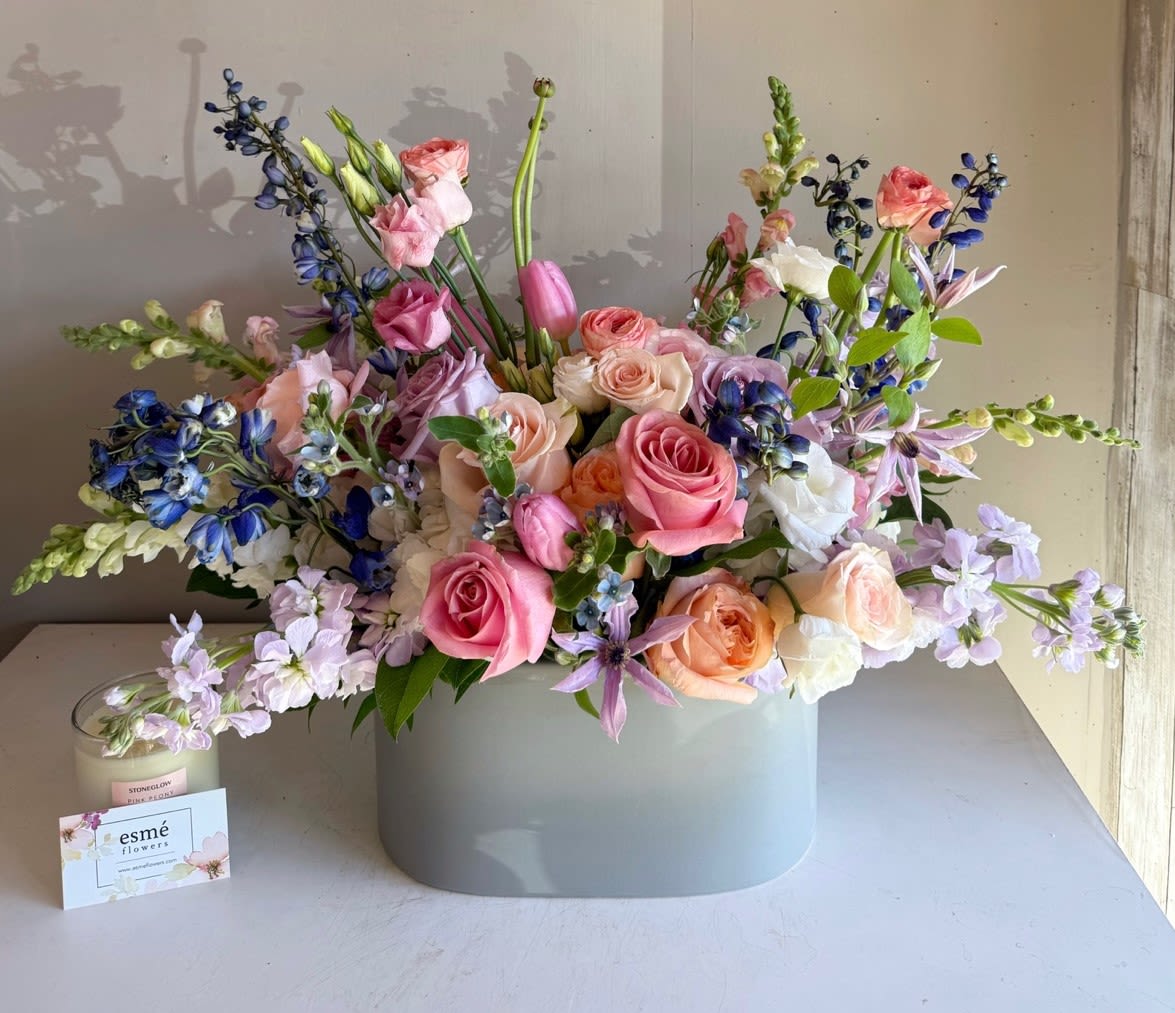 Pastel bouquet of roses, tulips, and blue flowers in a gray vase