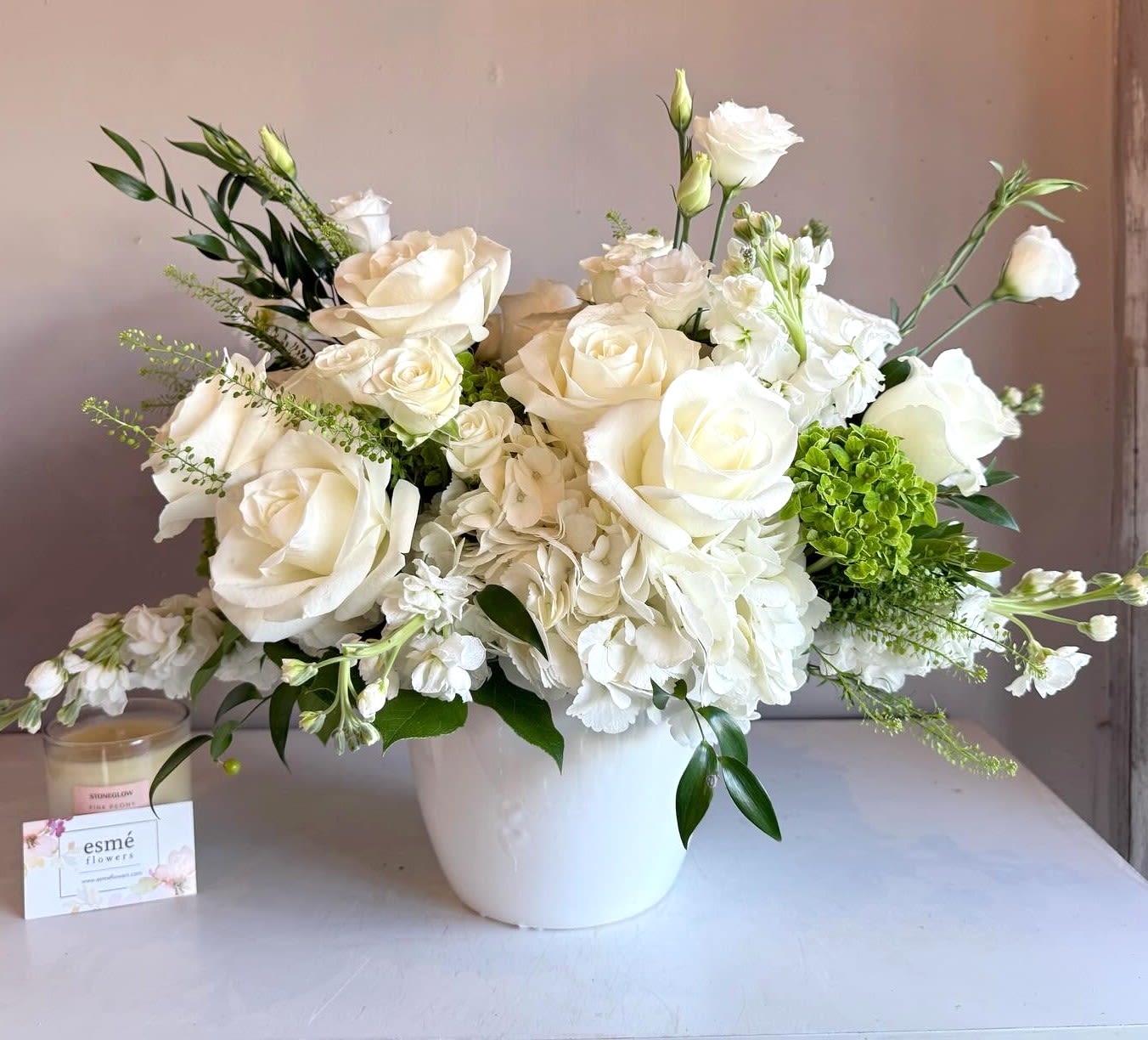White roses and hydrangeas arranged in a white vase