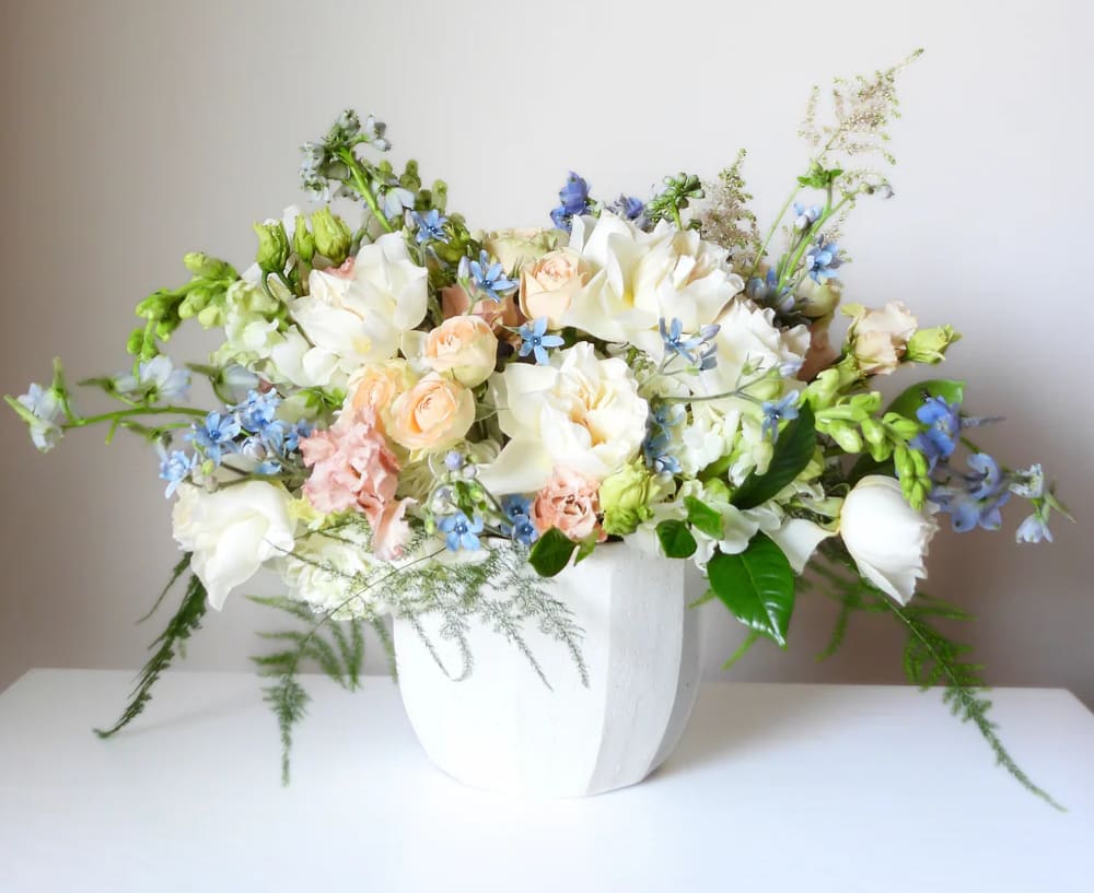 White and peach floral arrangement in a white vase