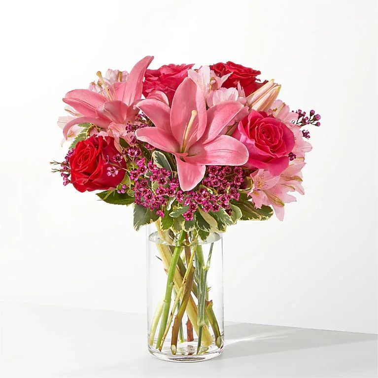 Pink lilies and red roses in a clear glass vase