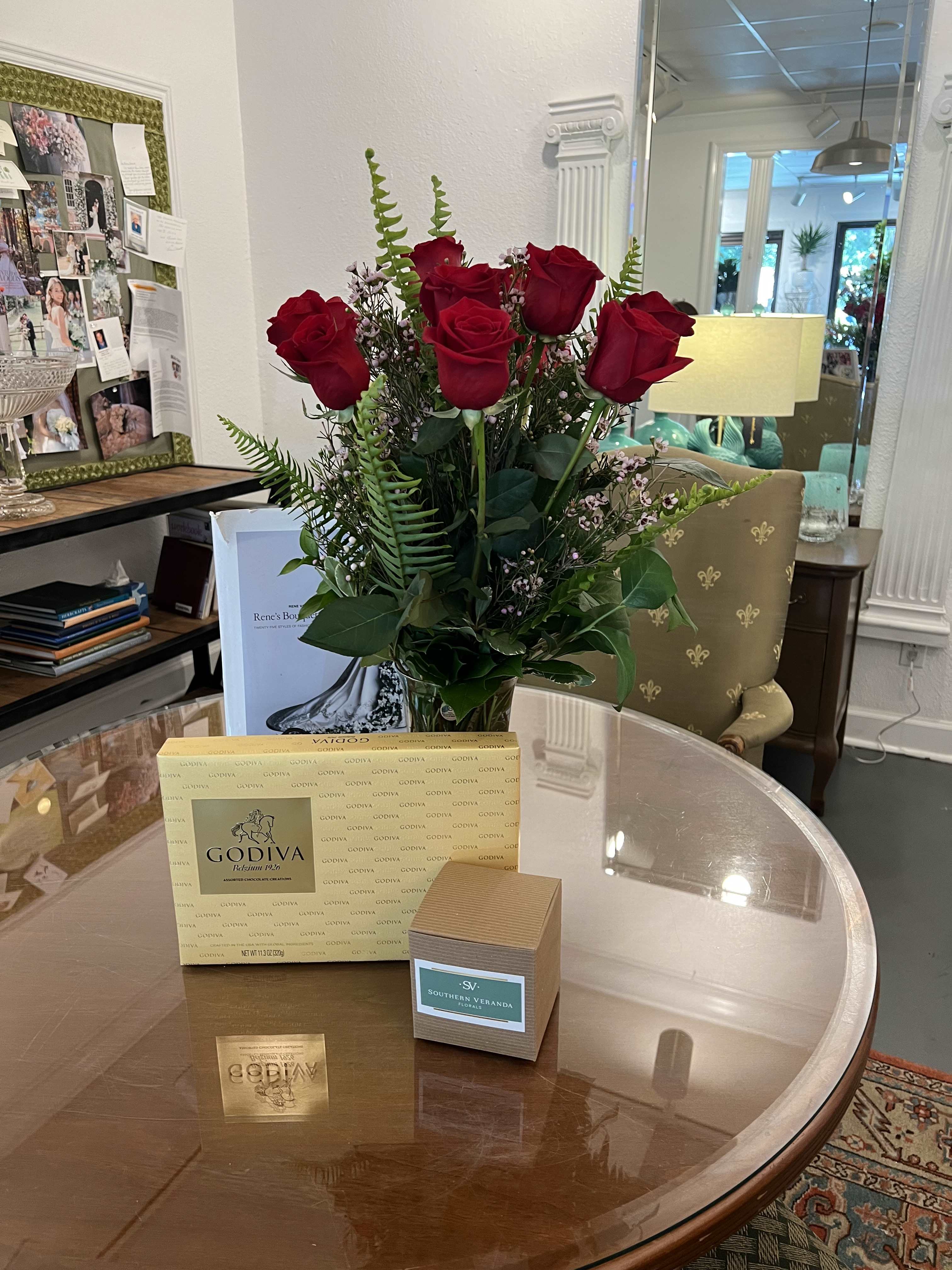 Bouquet of red roses in a glass vase with chocolates on a table
