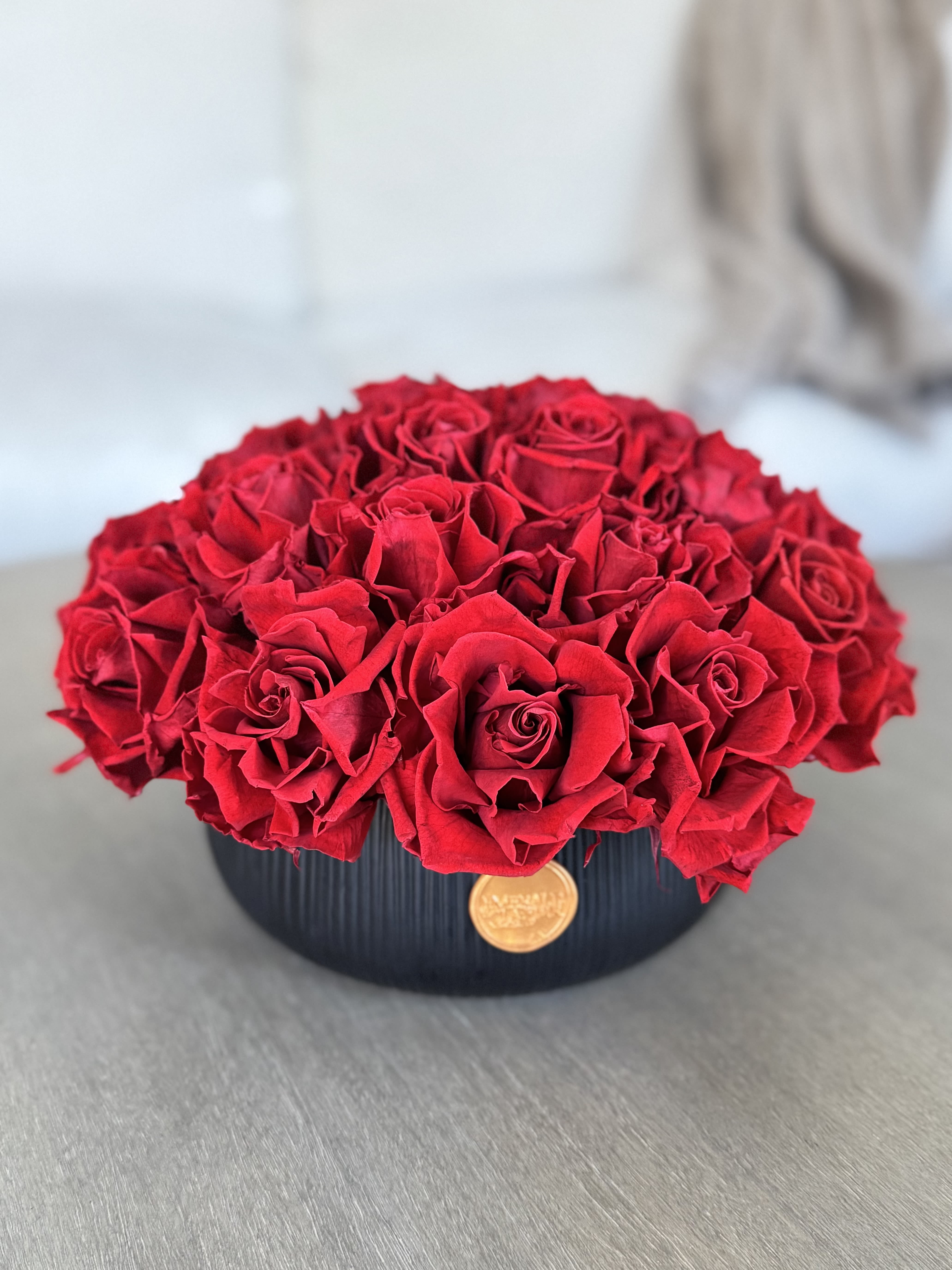 Round arrangement of red roses in a black vase
