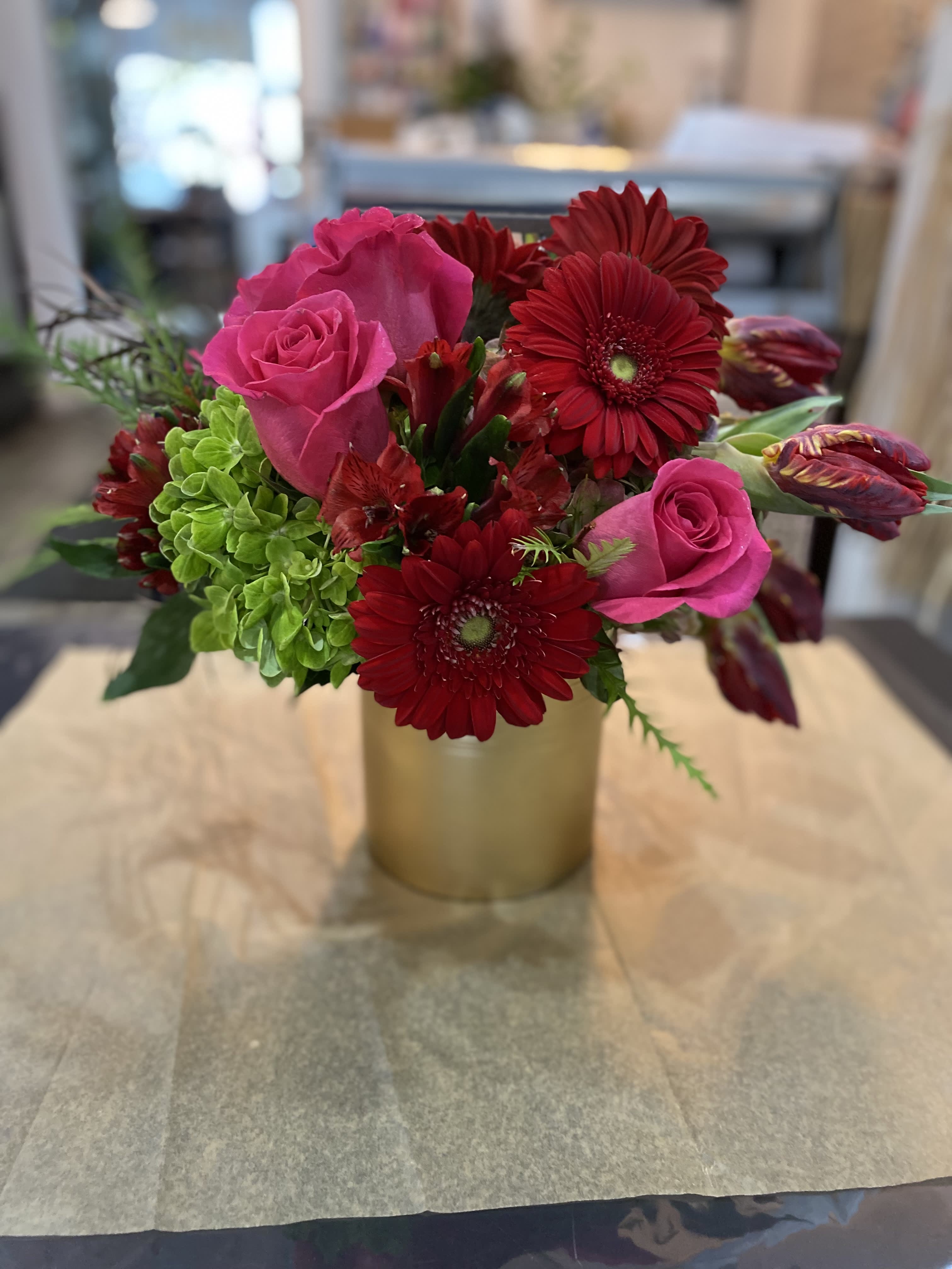 Pink roses and red gerbera daisies in a gold vase