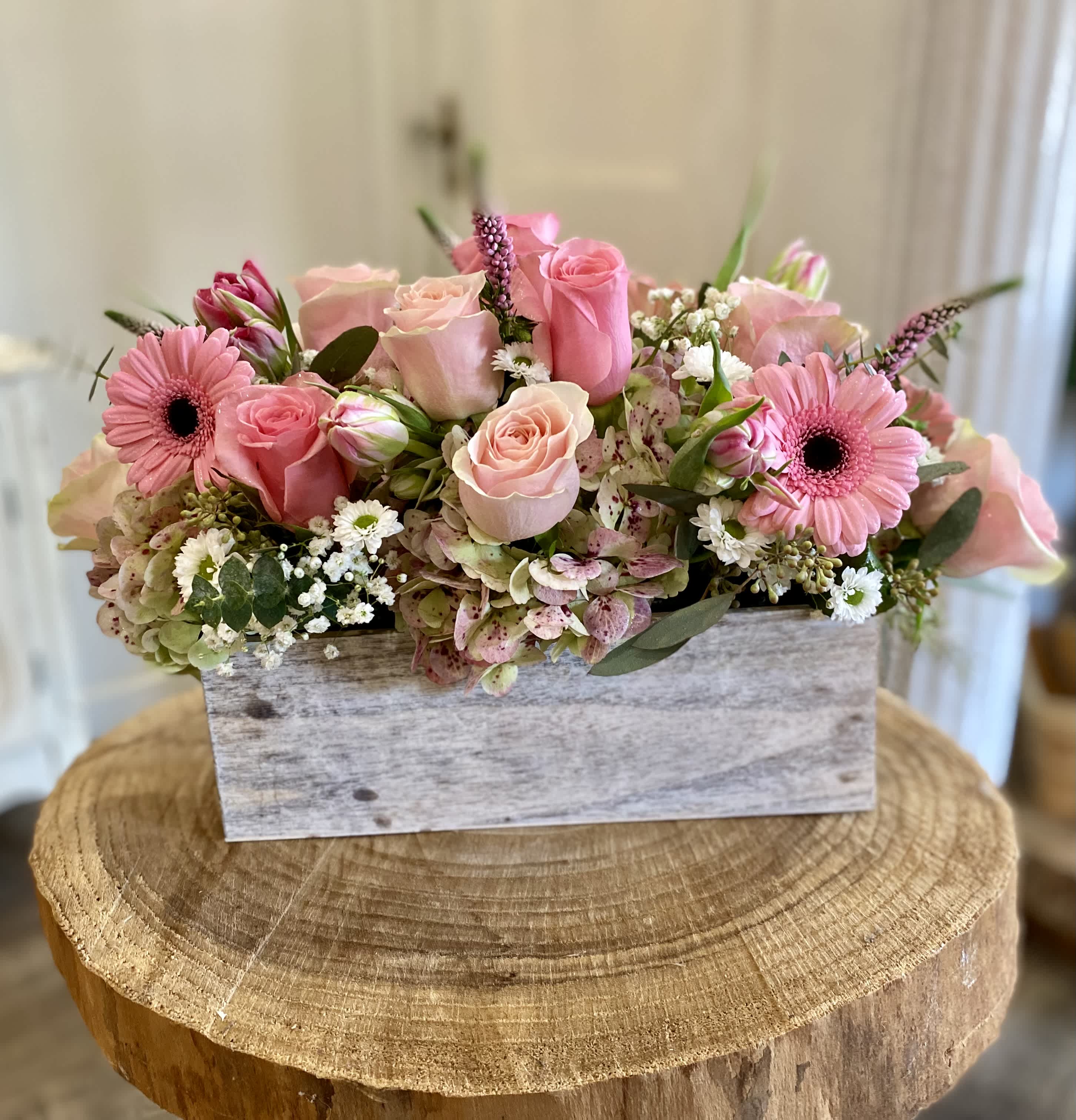 Pink roses and gerbera daisies arranged in a rustic wooden box