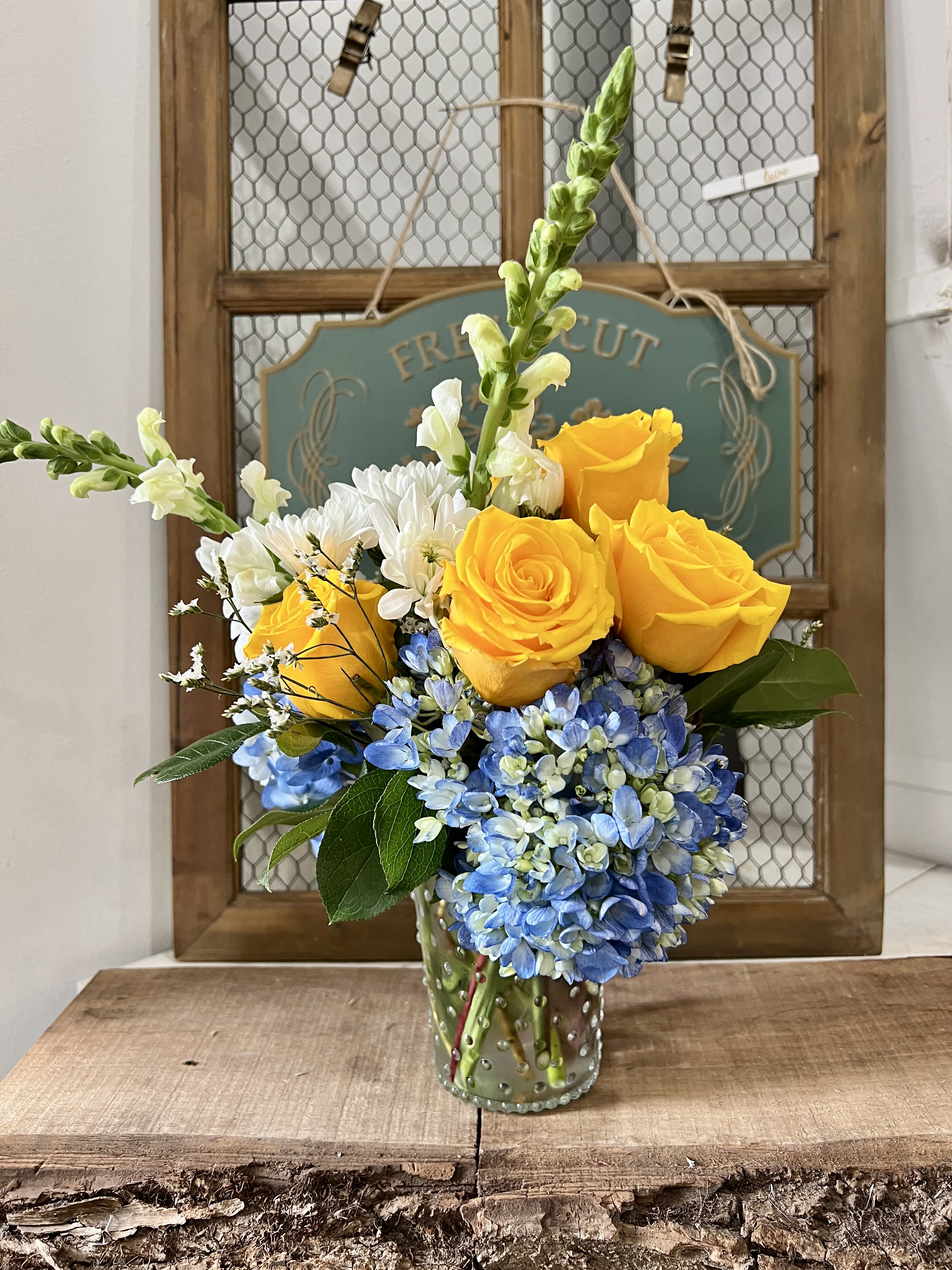 Yellow roses and blue hydrangeas in a glass vase