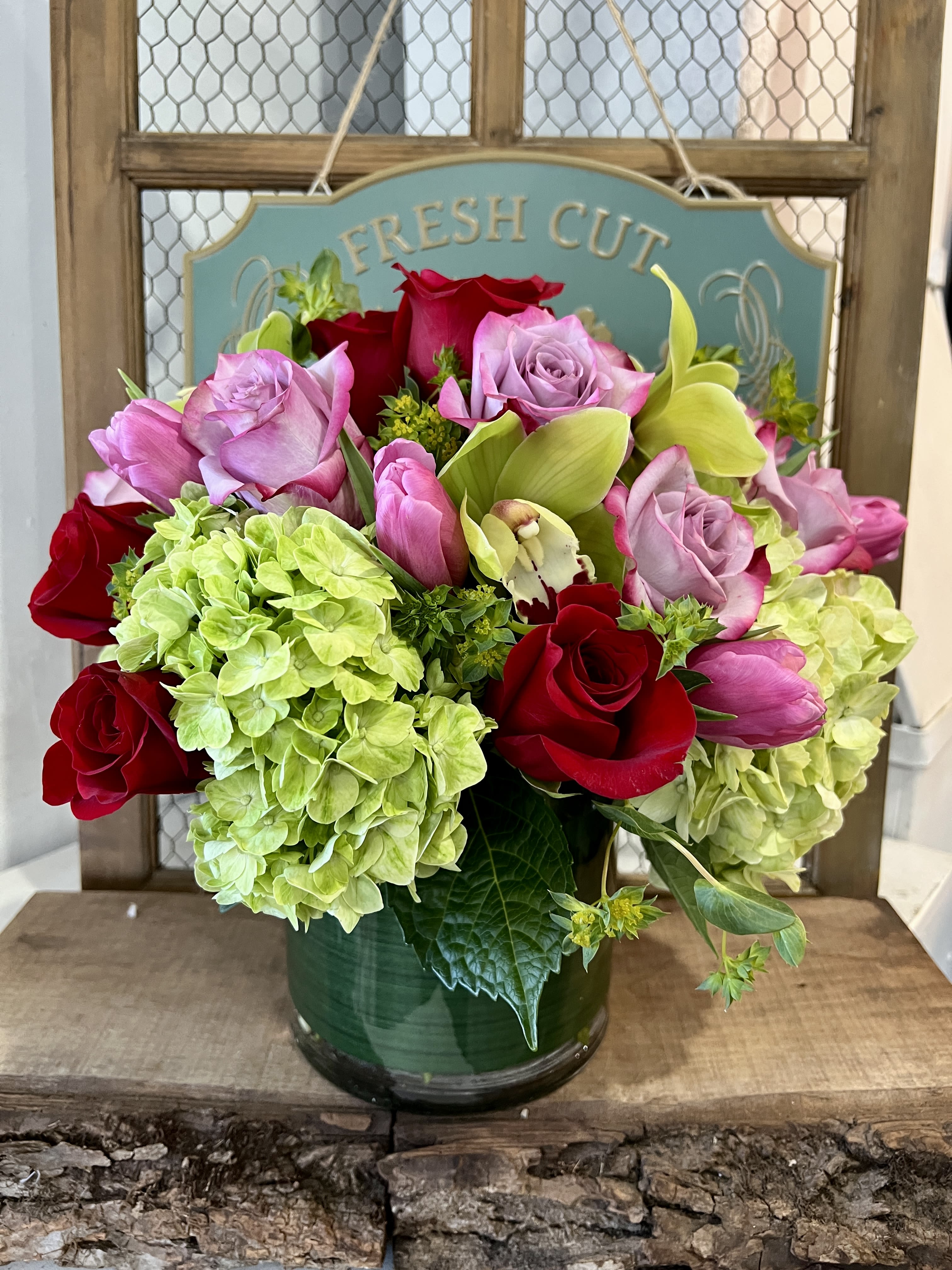 Bouquet of red and pink roses with green hydrangeas in a glass vase