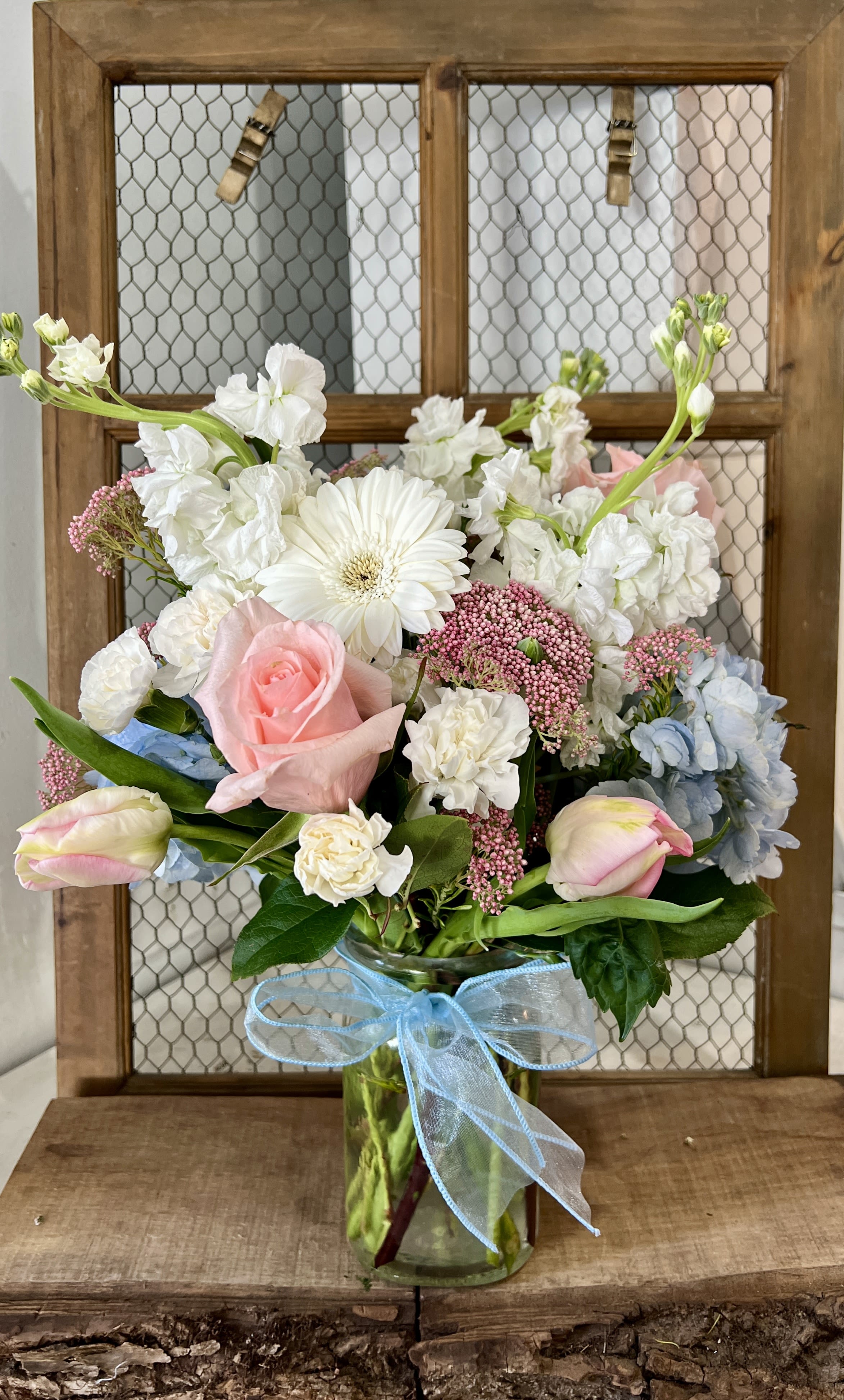 Pastel bouquet in a glass vase with a blue ribbon