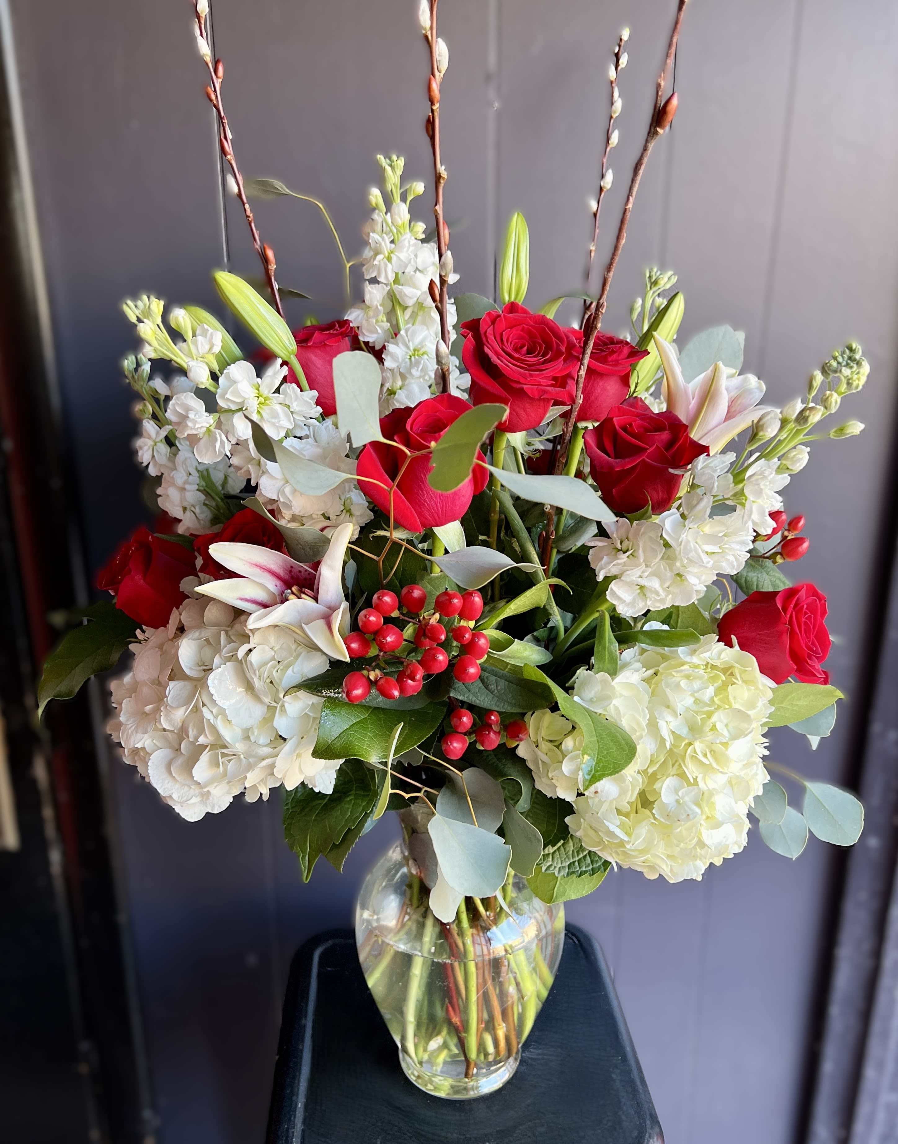 Red roses and white flowers arranged in a clear glass vase