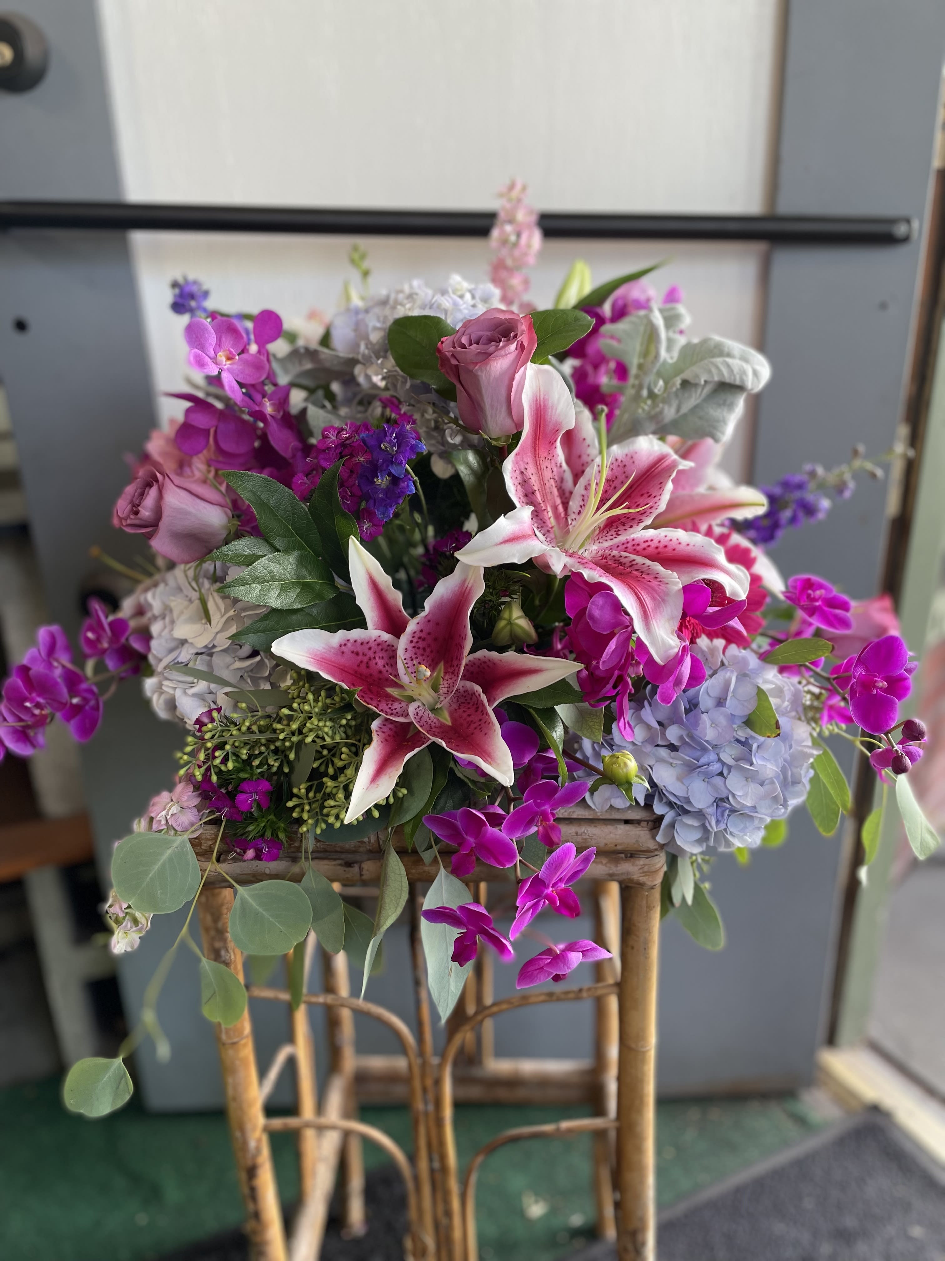 Mixed bouquet with pink lilies, roses, and purple orchids in a basket