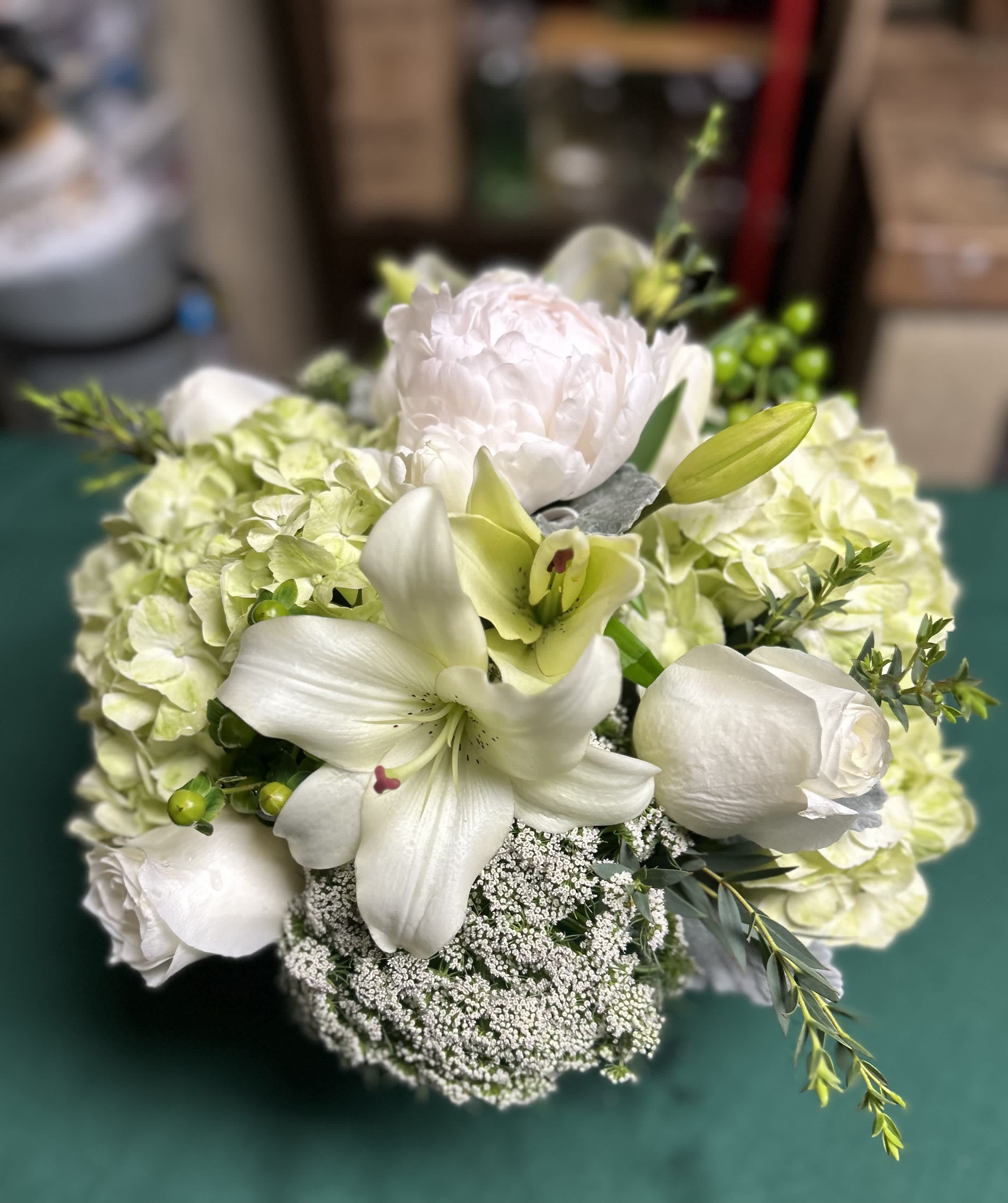 White floral bouquet with lilies, roses, and pale hydrangeas