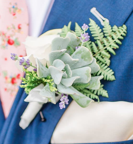 Boutonniere with pale succulent and lavender accents on a blue suit