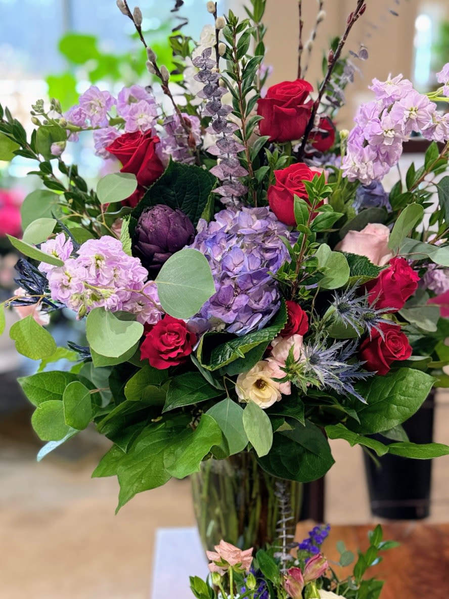 Bouquet of red roses and lavender flowers in a glass vase