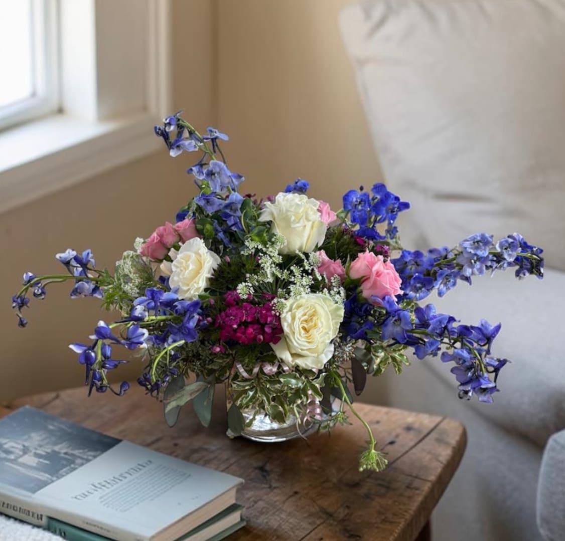 Bouquet of pink and white roses with blue flowers in a glass vase