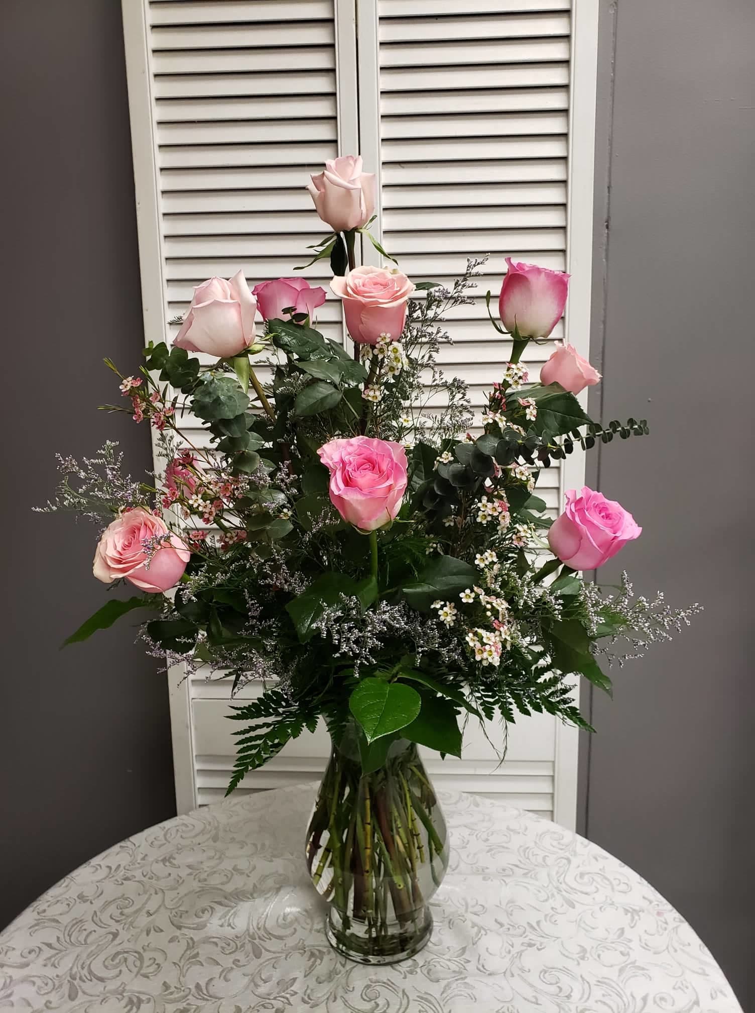 Tall arrangement of light and bright pink roses with delicate white fillers in a clear glass vase