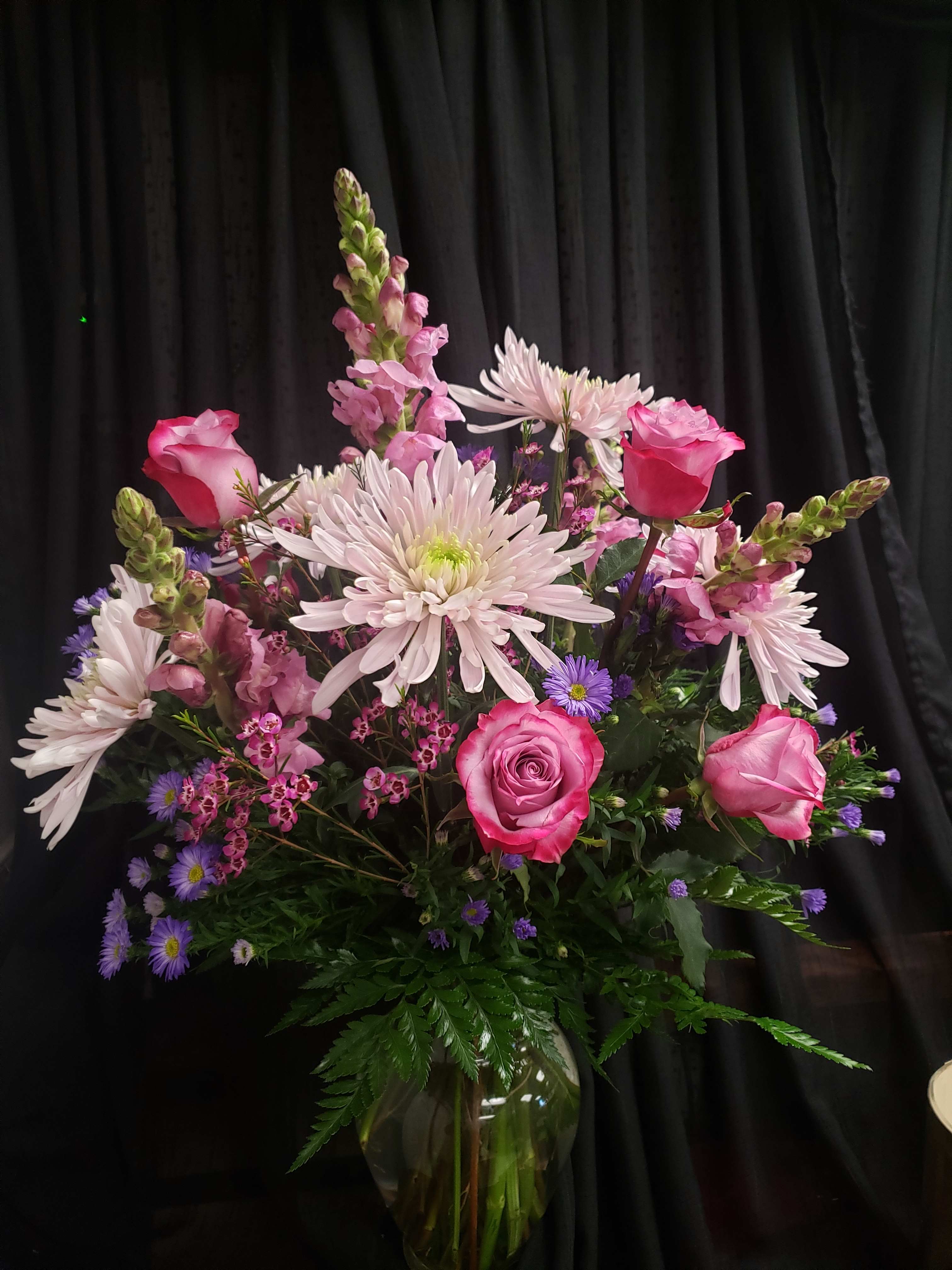 Pink roses and pale daisies arranged in a glass vase