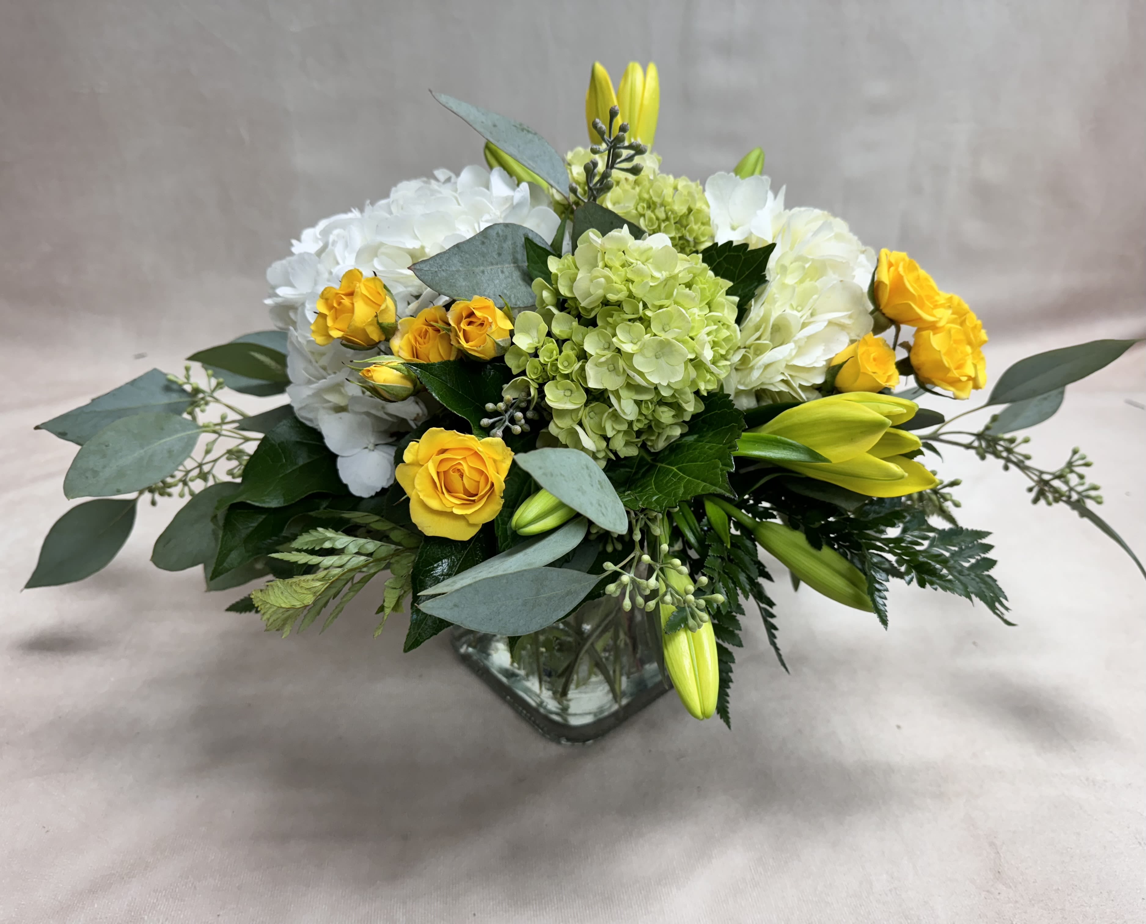 Yellow roses and white hydrangeas in a glass vase