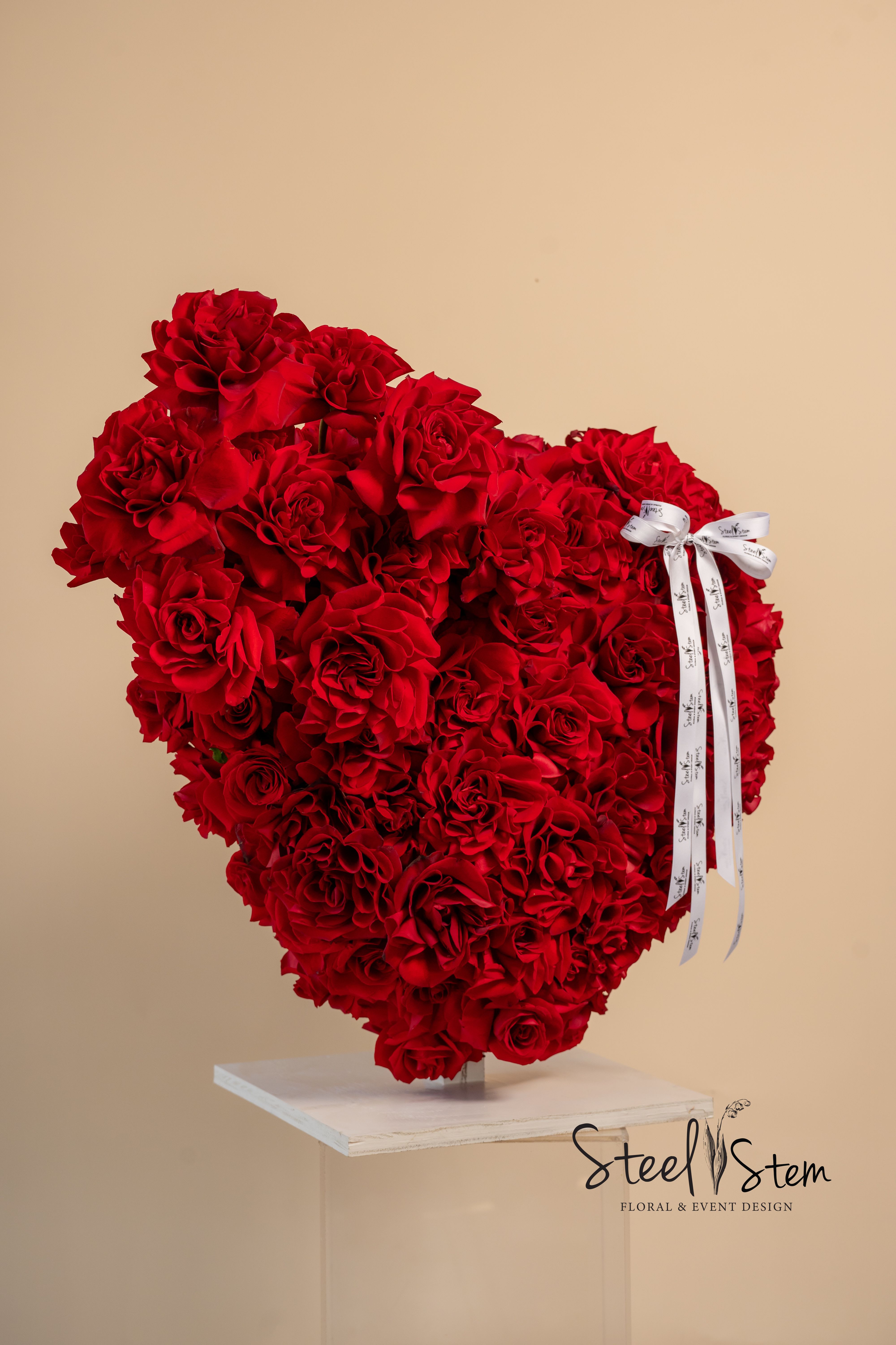 Heartbeat of Roses  - Love, passion, and devotion come to life in A Heartbeat of Roses. This 24” x 24” heart-shaped masterpiece is crafted with lush red roses, each petal with emotion. A symbol of deep love and timeless beauty. Because love, like a heartbeat, never fades.