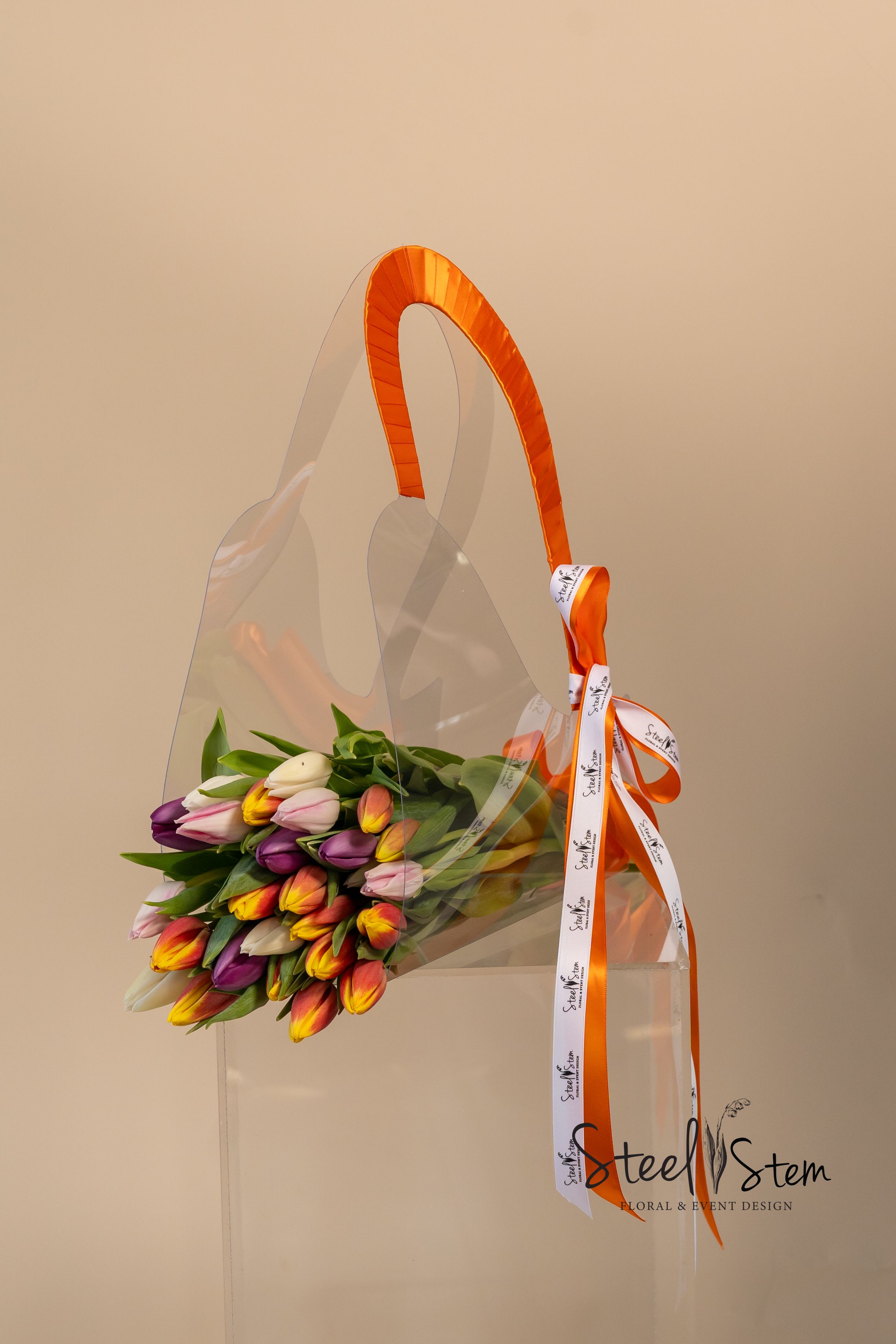 Bouquet of multicolored tulips in clear wrap with an orange ribbon