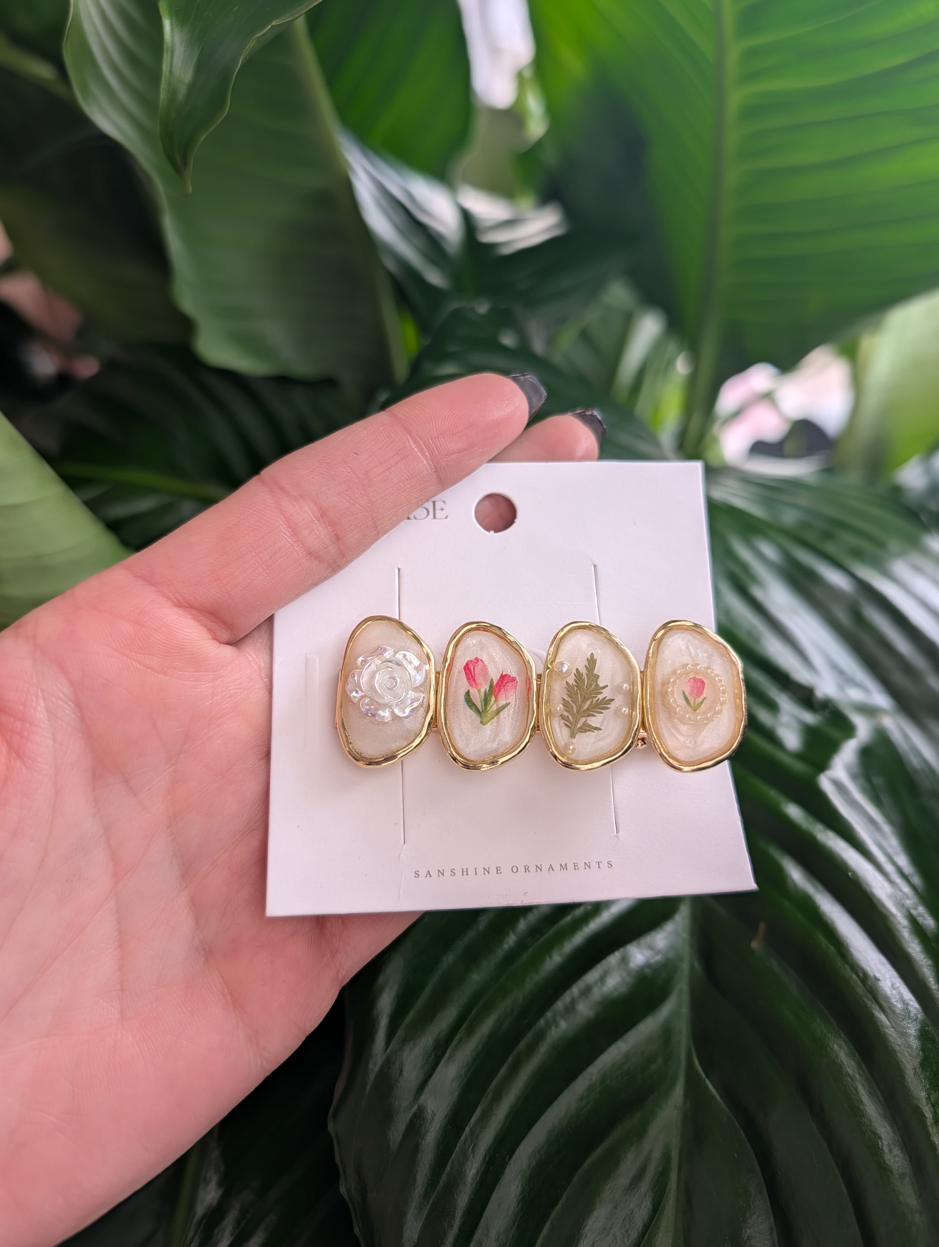 Hand holding a card with four floral resin hair clips