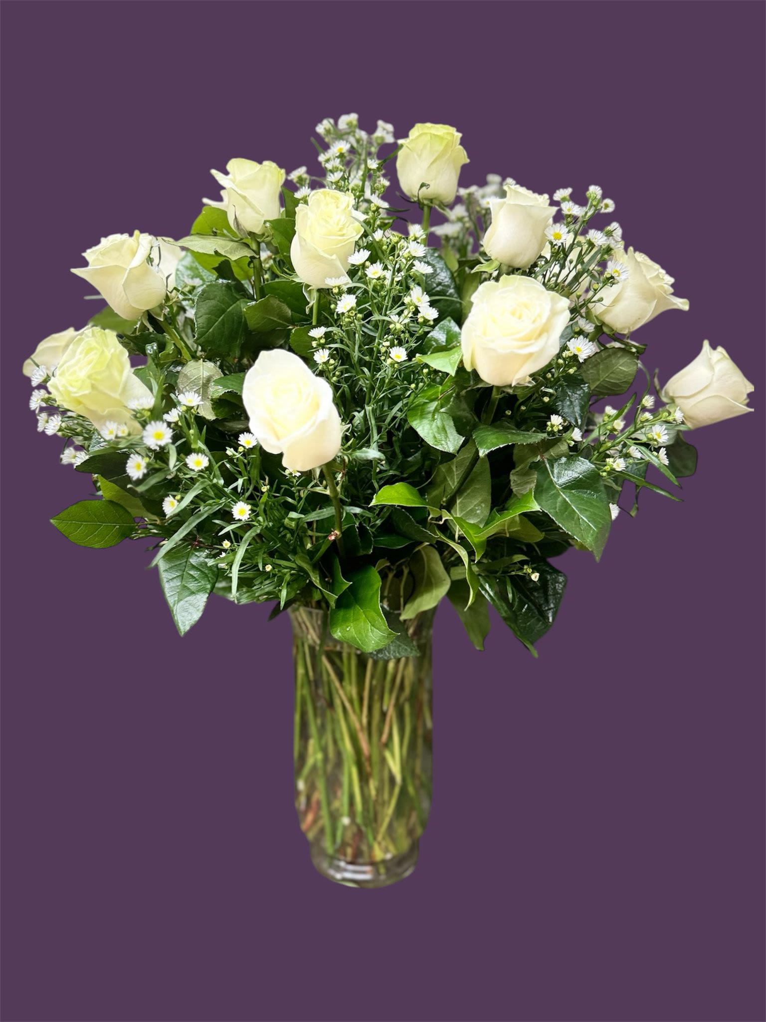 White roses in a clear glass vase with small white filler flowers