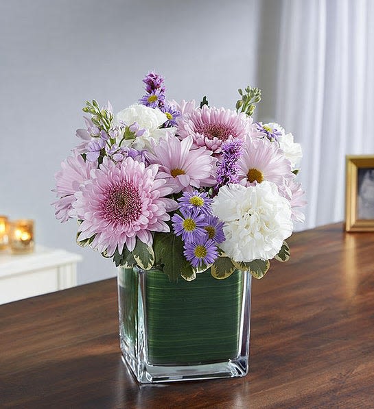 Pink and white flowers arranged in a clear square vase