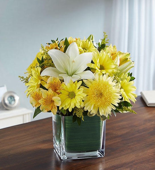 Yellow and white flower arrangement in a square glass vase