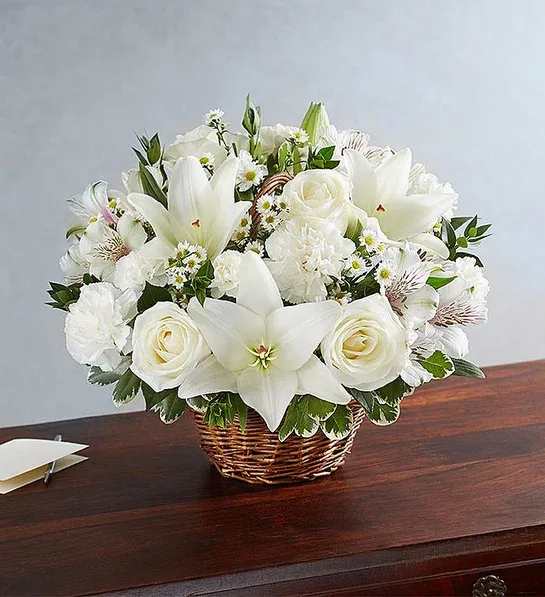 White lilies and roses arranged in a wicker basket