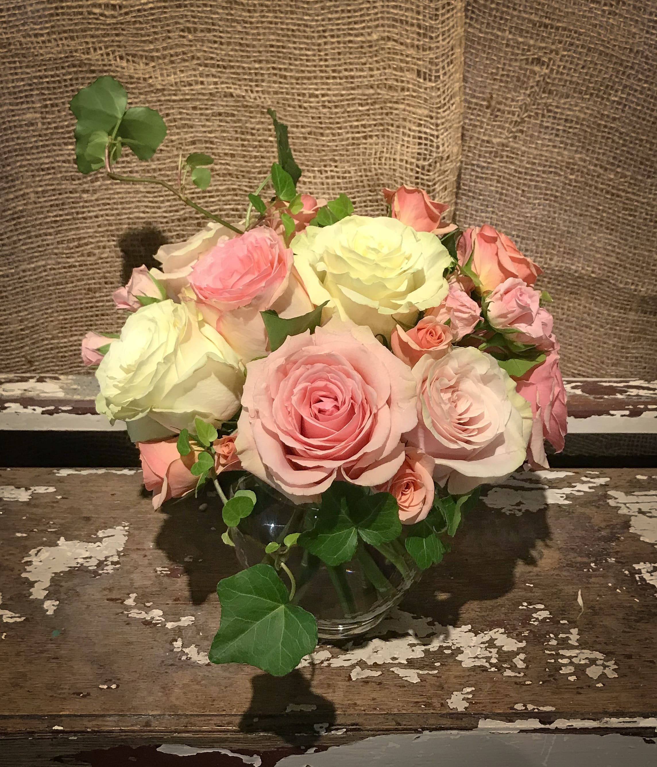 Pink and cream roses arranged in a clear glass vase