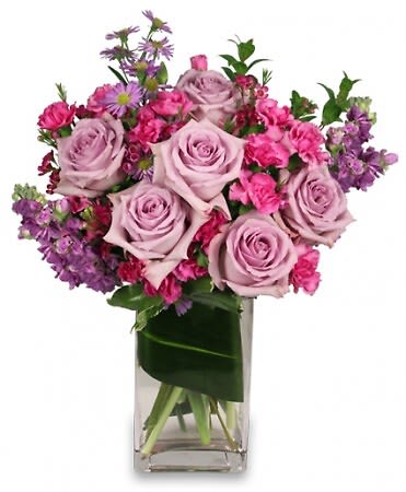 Lavender Luxury - They'll love getting this luscious bouquet! Featuring lavender roses, fuchsia mini carnations, lavender stock, lavender asters, and purple waxflowers, Lavender Luxury is a natural beauty full of sweet fragrance. Delightful and charming, this stunning bouquet is sure to brighten anyone's day!  Includes Rectangular Glass Vase Foliage: Aspidistra Leaf, Myrtle , Lavender Roses , Lavender Stock , Fuchsia Mini Carnations , Lavender Asters (Monte Casino) , Purple Waxflowers.