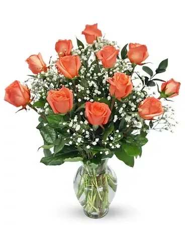 Orange roses arranged in a clear glass vase with baby's breath