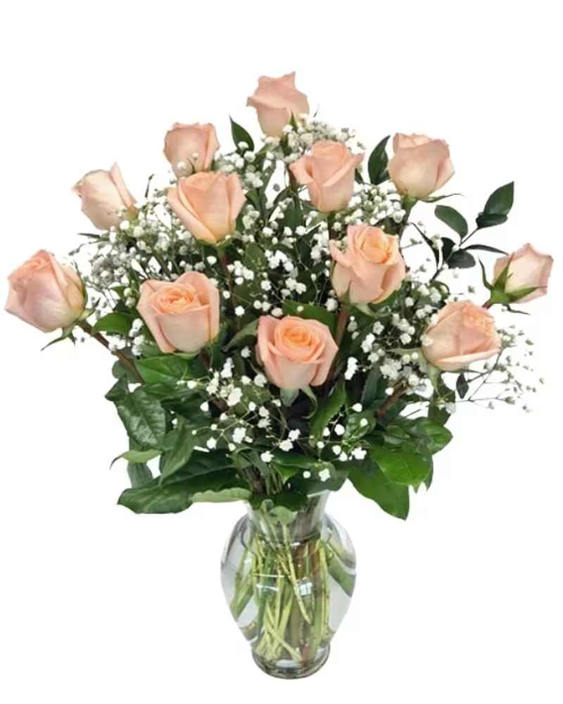 Peach roses arranged in a clear glass vase with baby's breath