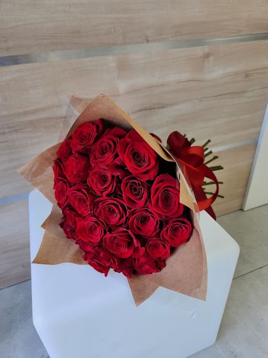 Large bouquet of red roses wrapped in brown paper and tied with a red ribbon