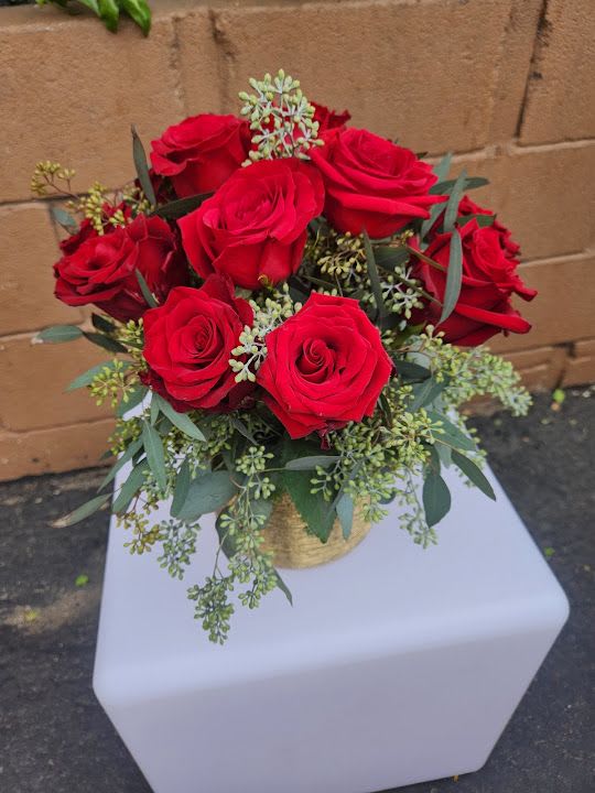 Arrangement of red roses in a gold vase on a white pedestal
