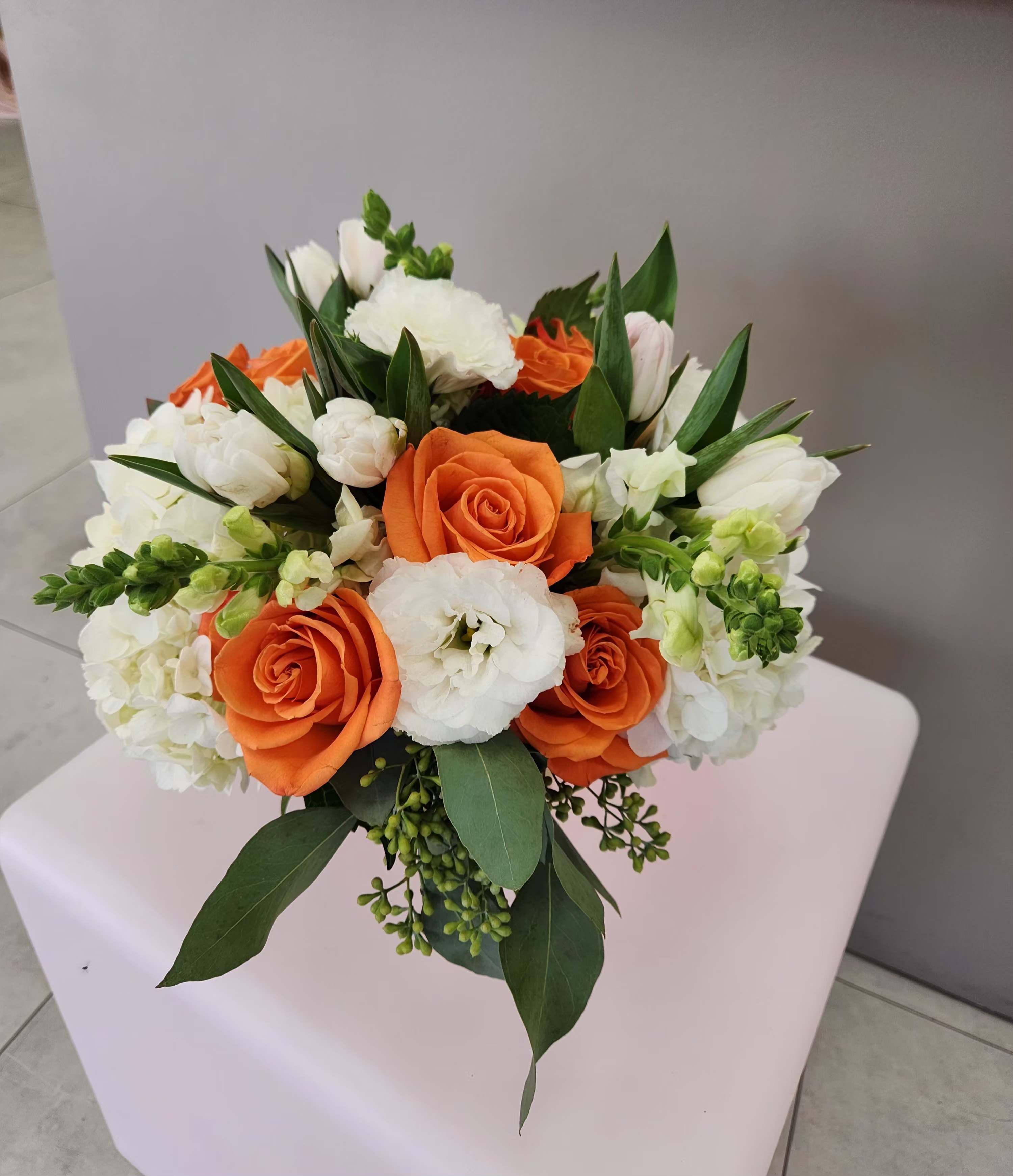 Round arrangement of orange roses and white blooms with green accents in a compact mixed bouquet