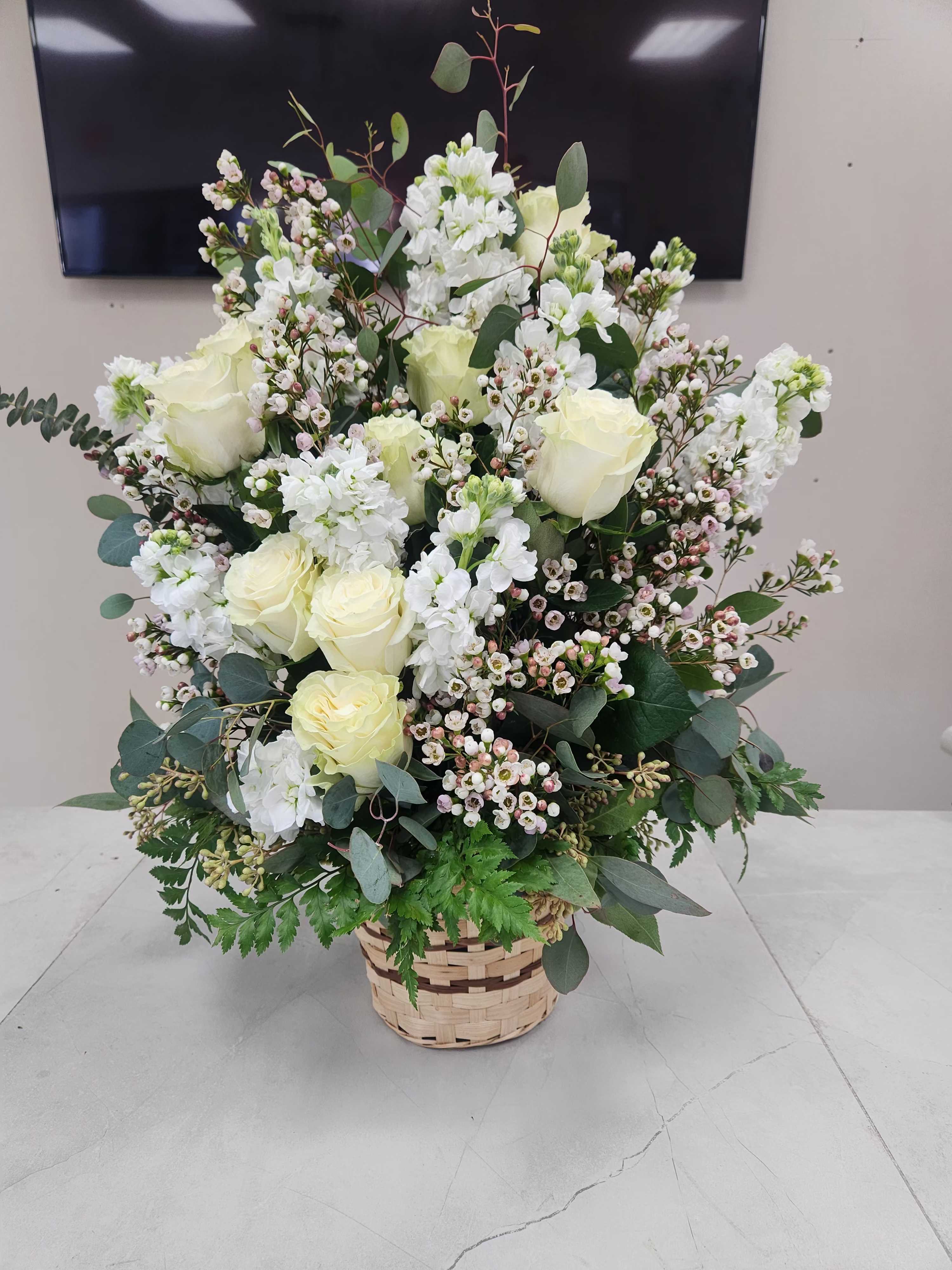 Tall basket arrangement of white roses and white blooms with small blush accents