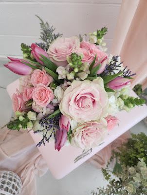 Hand-tied bouquet of soft pink roses, pink tulips, and white blooms in a compact round design