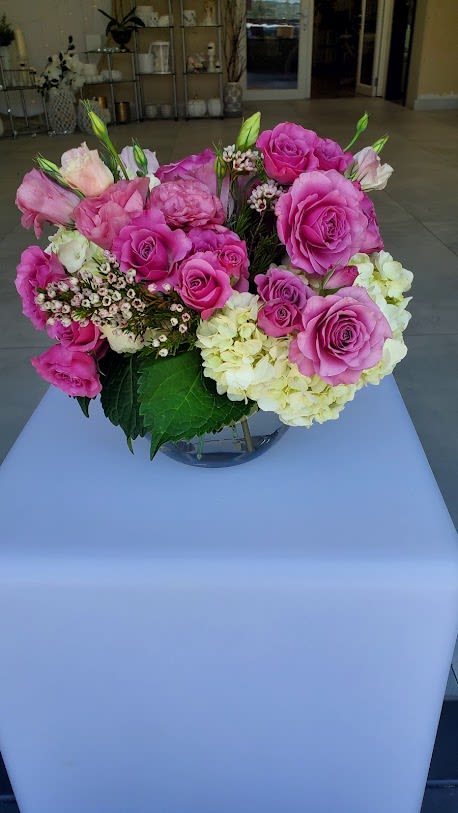 Low arrangement of pink roses and pale hydrangeas in a clear glass bowl vase