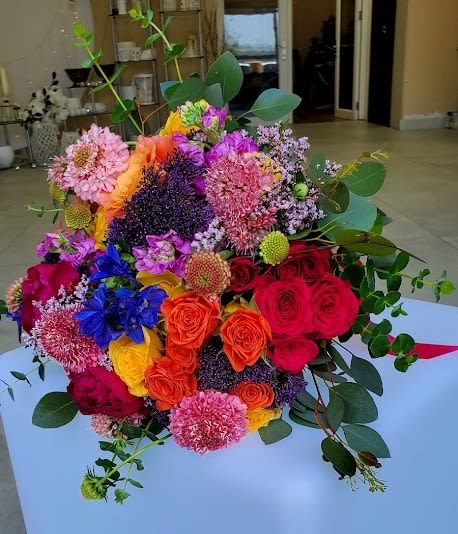 Colorful hand-tied bouquet of roses and mixed blooms in bright pink, orange, yellow, and purple tones