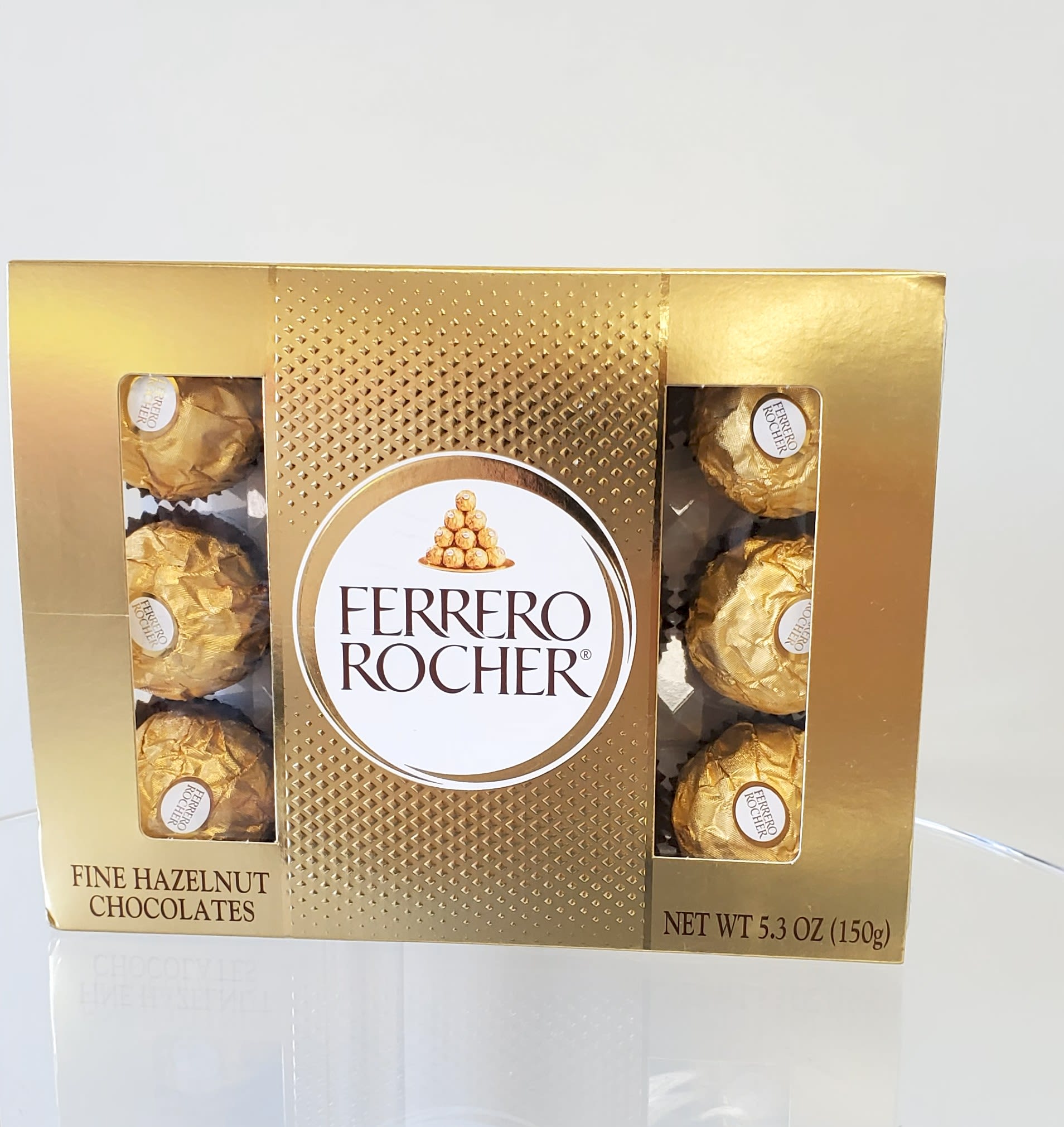 Gold box of Ferrero Rocher hazelnut chocolates on a clear surface