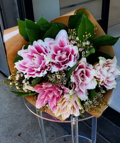 Hand-tied bouquet of pink and white blooms wrapped in brown paper
