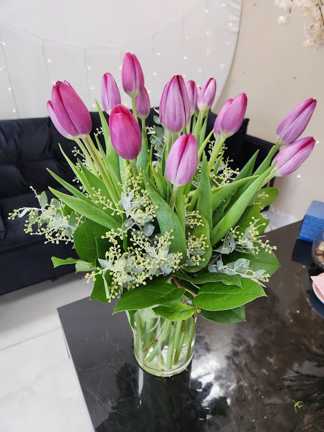Bouquet of pink and purple tulips arranged in a clear glass vase on a table