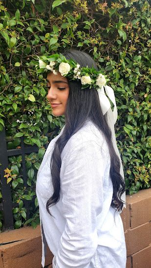 Woman wearing a white rose and greenery flower crown with trailing white ribbon