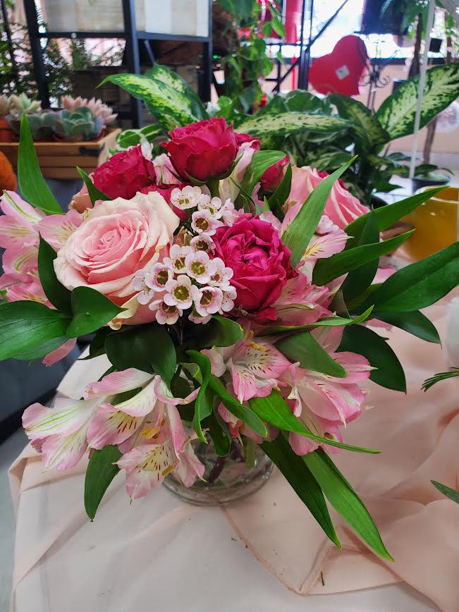 Pink and red roses with pink alstroemeria in a clear glass vase.