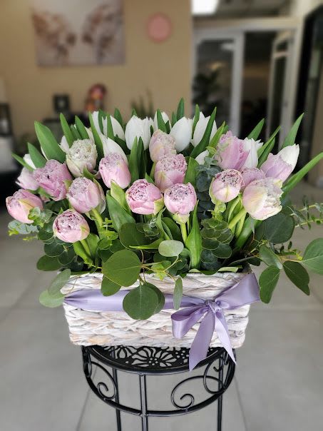 You're Special - Dense cluster of pink, white tulips in a white woven basket finished with lavender satin ribbon
