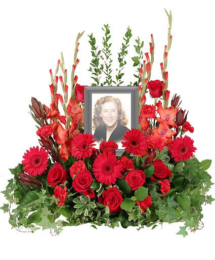 Adoration - Relive fond memories and celebrate the life of someone near and dear to your heart with a beautiful Adoration memorial arrangement. Gerberas, roses, and carnations in traditional red hues surround a photograph of your loved one. Picture Frame not Included  Includes Casket Saddle With Wet Floral Foam, Foliage: Salal, Pittosporum, Ivy, Myrtle, Safari Sunset Leucadendron, Red Gladiolus, Red Gerberas, Red Roses, Red Carnations.