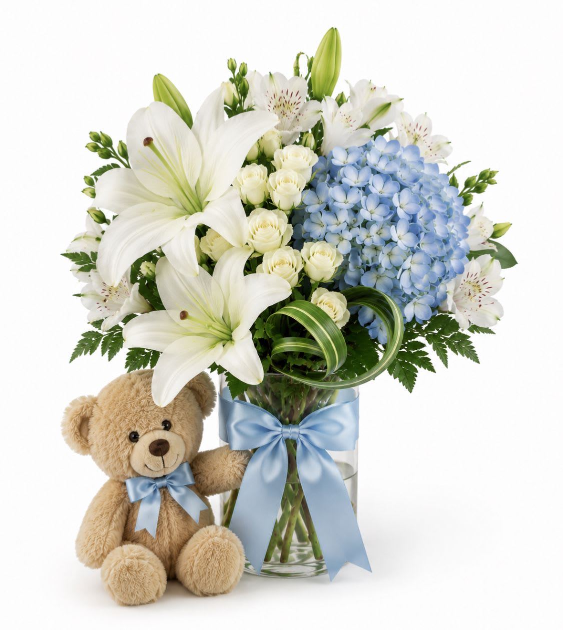  Baby Boy Big Hug Bouquet - Soft white lilies and a pale blue hydrangea form a tender, celebratory bouquet designed to welcome a new baby boy - perfect as a new baby gift or a gentle sympathy arrangement. The compact presentation in a pale blue ceramic or clear glass vase, finished with a blue satin ribbon and a small light-blue teddy bear, reads as both joyful and comforting; she'll feel truly seen whether you're congratulating new parents or offering condolences during a difficult time.  This arrangement mixes Asiatic lilies and large white lilies with a rounded cluster of light blue hydrangea, yellow and spray roses, white alstroemeria, and lush greenery for a soft, airy palette of white, blue, yellow, pink, and green. Flowers arrive neatly arranged to showcase the lilies' dramatic petals and the hydrangea's cloud-like texture; the vase choice and coordinating ribbon tie the look together while the plush bear adds a keepsake touch.  A thoughtful pick for hospital visits, newborn celebrations, or as a sympathy vase that brings calm and warmth, the bouquet is delivered ready-to-display so the recipient can enjoy its scent and presence immediately. Standard care: keep blooms in fresh water, recut stems every few days, and remove spent flowers to prolong the arrangement's life.
